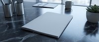 Modern minimalist office workspace with blank white paper document on dark marble desk surface alongside coffee cup and succulent plant for business presentations.