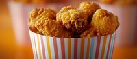 Crispy golden fried chicken wings in colorful striped paper container, served as appetizer or snack for parties, sports events, or casual dining.