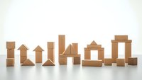 Wooden building blocks arranged in architectural structures on white background for educational play and creative construction activities.