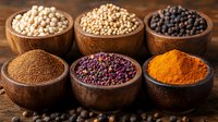 Aromatic spices and legumes in wooden bowls on rustic table including turmeric powder, black peppercorns, chickpeas and mustard seeds arranged in rows.