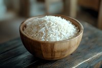 Raw white rice grains in wooden bowl on rustic table, natural food ingredient for cooking Asian cuisine.