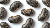 Black and white speckled dry beans scattered on white background, isolated food ingredient pattern for cooking and healthy eating designs.