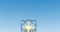 Light bulb inside ice cube against clear blue sky, symbolizing innovation, cool ideas, and sustainable energy solutions for business and technology concepts.