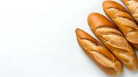 Fresh crusty French baguettes arranged on white wooden background, golden brown artisanal bread loaves with crispy crust and classic scoring pattern.