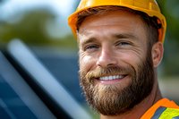 Confident construction worker with full beard and yellow hard hat smiling outdoors. Professional portrait showing reliability and expertise in building industry.