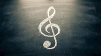 White treble clef symbol drawn in chalk on dark textured floor surface with dramatic lighting creating atmospheric musical concept for creative projects.