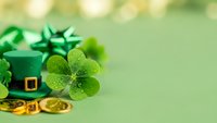 Green leprechaun hat with shamrock clover and gold coins on soft bokeh background for St Patricks Day celebration and Irish holiday decorations.