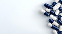 Blue and white medical capsules scattered on white background, pharmaceutical drug composition with copy space for healthcare and medicine design.