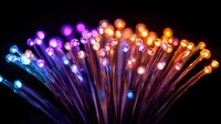 Vibrant fiber optic strands spreading in fan shape with glowing blue, purple, pink and orange lights against dark background create mesmerizing light display.