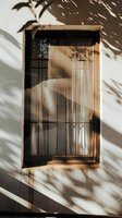 Window with palm tree shadows casting dramatic patterns on white wall during golden hour sunlight, creating moody atmospheric composition.