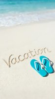 Vacation written in sandy beach with turquoise flip flops beside ocean waves, evoking summer travel and tropical holiday relaxation.