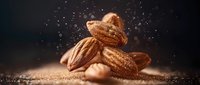Fresh almond nuts falling with gold dust splash effect on dark background, macro food photography with dramatic lighting and copy space.