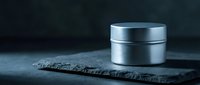 Luxury silver cosmetic jar on dark slate surface with moody lighting for premium skincare and beauty product packaging design.