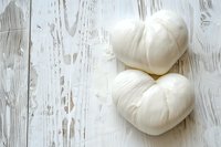 Fresh white garlic bulbs shaped like hearts on rustic weathered wooden background with copy space. Natural food photography for cooking blogs.