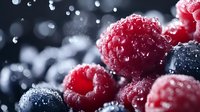Fresh mixed berries with water droplets including raspberries and blueberries creating vibrant red and blue colors for healthy eating and nutrition concepts.