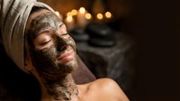 Young woman relaxing with chocolate face mask treatment at luxury spa with warm ambient lighting for skincare and wellness therapy.