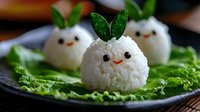 Cute rice balls shaped as bunnies with carrot faces and green leaf ears, served on fresh lettuce leaves against dark plate, creative Asian food styling.
