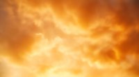 Dramatic orange storm clouds with glowing sunlight breaking through turbulent formations create atmospheric sky background for weather and nature designs.