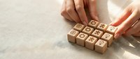 Female hands arranging wooden blocks with business icons on light surface for corporate strategy and planning concepts.