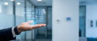 Businessman's hand holding digital interface with data analytics icons in modern office environment for technology and business solutions.