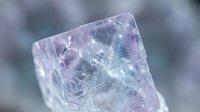 Natural purple fluorite crystal specimen with transparent faceted surfaces and internal fractures displaying geological mineral formation structure.