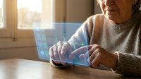 Senior woman using futuristic holographic tablet interface with digital icons at home, elderly person interacting with advanced technology display.
