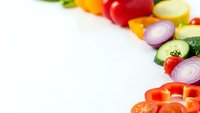 Fresh colorful vegetables arranged as border on white background with copy space for healthy cooking and nutrition concepts.