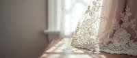 Elegant white lace curtain with intricate floral embroidery filtering soft natural light in cozy home interior for romantic decor and textile design.