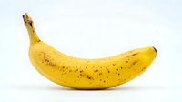Ripe yellow banana with brown spots isolated on white background, ready for food and nutrition design projects.
