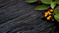 Fresh orange berries with green leaves arranged on rustic dark wooden surface for natural organic food photography and botanical design projects.