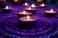 Glowing tea light candles arranged in circular pattern on ornate purple textile surface create atmospheric mood lighting for meditation and spiritual practices.