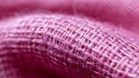 Pink woven cotton fabric macro shot showing detailed textile texture and fibers in soft focus with shallow depth of field and dreamy atmosphere.