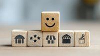 Wooden blocks with business icons and smiley face symbolizing positive customer experience and retail satisfaction in commerce environment.