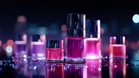 Colorful nail polish bottles on reflective surface with bokeh lights background in pink and purple neon colors creating glamorous beauty composition.