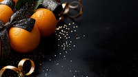 Fresh oranges with black glitter ribbon and gold curled streamers on dark background, festive holiday composition with copy space for text and design.
