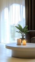 Minimalist living room corner with glowing candles and green plant on round coffee table, soft natural light through sheer curtains creates peaceful ambiance.