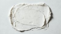 Thick white cream or plaster spread on neutral background, isolated texture for design projects, packaging mockups, and cosmetic product presentations.