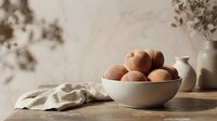 Rustic still life arrangement featuring fresh potatoes in a ceramic bowl on wooden surface with neutral tones and natural lighting for culinary and home decor projects.