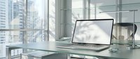 Modern laptop with blank white screen on glass desk in contemporary office workspace with city skyline view through large windows for business presentations.