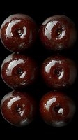 Fresh dark red cherries arranged in rows on black background, showing glossy surface and natural highlights. Macro food photography for culinary use.