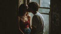 Intimate couple embracing by window in moody lighting, romantic relationship moment with emotional connection and tender affection between partners.