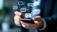 Glowing message bubbles and email icons floating above smartphone screen held by business professional in dark suit, illustrating digital communication concept.
