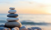Balanced zen stones pyramid on beach at sunset with blurred ocean background, creating peaceful atmosphere for wellness and meditation practices.