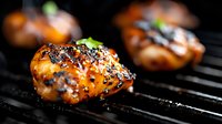 Grilled chicken thighs glazed with sweet and savory Asian marinade, garnished with black sesame seeds and green onions on barbecue grill grates.