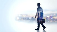 Double exposure businessman walking with city skyline overlay against bright background representing urban professional success and corporate ambition.
