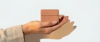Hand holding small brown cardboard boxes on neutral background for shipping delivery and e-commerce business concepts.