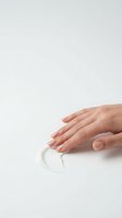 Woman's hand with manicured nails touching white cosmetic cream or skincare product on isolated background. Suitable for beauty, wellness and dermatology marketing.
