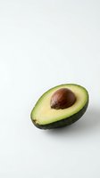 Fresh ripe avocado half with pit on white background isolated for healthy cooking and nutrition design projects.