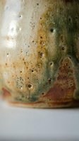 Close-up of handmade ceramic pottery with natural earth tones, organic textures and artisan glazing techniques showing rustic craftsmanship details.