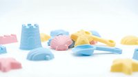 Colorful plastic toy building blocks and sand molds in blue, pink, and yellow arranged on white surface for children's creative play and development.